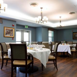 A well-lit dining room with elegantly set tables and comfortable chairs.