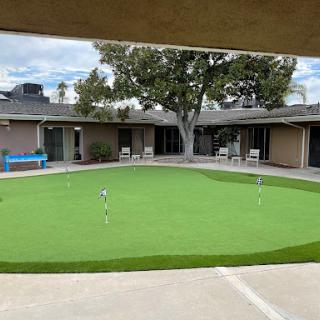 A well-maintained putting green surrounded by buildings, perfect for practice and relaxation.