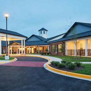 A beautifully landscaped entrance to a modern building during the evening.