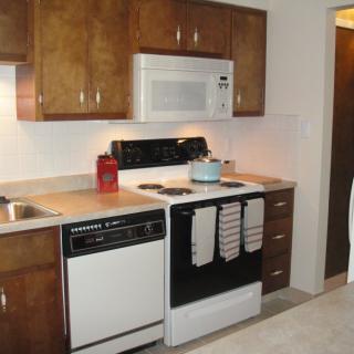 A modern kitchen featuring wooden cabinets, an oven with a stovetop, a microwave, and a dishwasher.