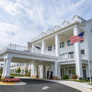 A grand building with columns and flags at the entrance, set against a partly cloudy sky.