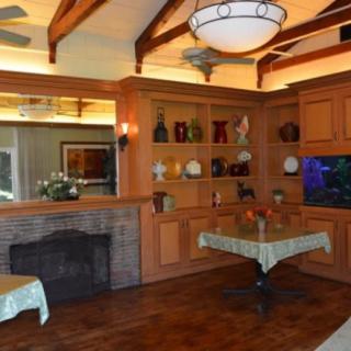 A cozy dining room featuring a fireplace, wooden ceiling beams, decorative shelves, and an aquarium.
