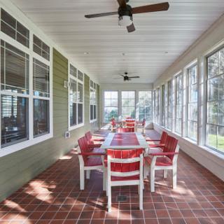 A spacious screened-in porch featuring a long dining table and comfortable chairs, perfect for gatherings.