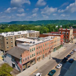 Aerial view of a downtown area with buildings, cars, and a scenic backdrop.