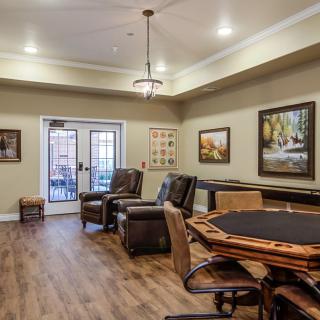 A cozy living room featuring comfortable chairs, a table, and artwork on the walls.