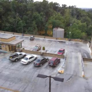 Aerial view of a parking lot with several parked vehicles surrounded by greenery.