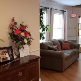 A cozy living room featuring a comfortable sofa, decorative flowers, and personal photographs.