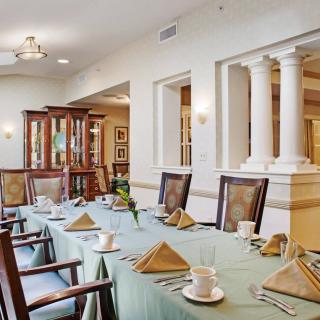An elegantly set dining room with a long table, neatly arranged chairs, and classical decor.