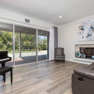 A modern living room featuring a grand piano, a cozy fireplace, and large sliding glass doors leading to a garden.