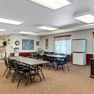 A spacious meeting room with tables and chairs arranged for a group setting.