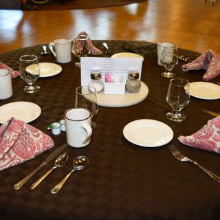 An elegantly set dining table with plates, cutlery, glasses, and folded napkins.