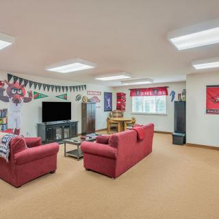 A cozy basement family room featuring red couches, a television, and various decorations.