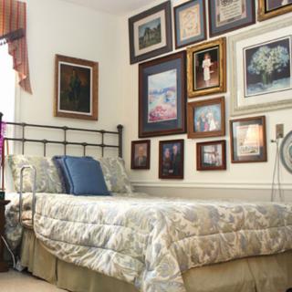 A cozy bedroom decorated with a collection of framed paintings on the wall.