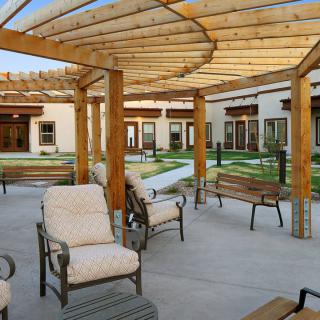 A spacious outdoor patio area featuring a wooden pergola and comfortable seating.