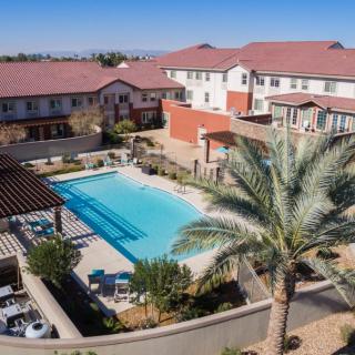 Aerial view of a hotel with a swimming pool surrounded by palm trees.