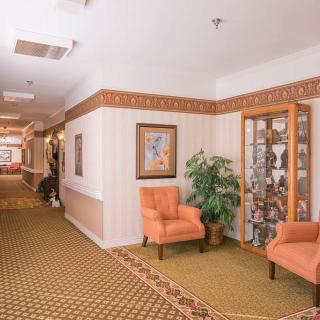 A well-decorated hallway with comfortable chairs, a display cabinet, and wall art.