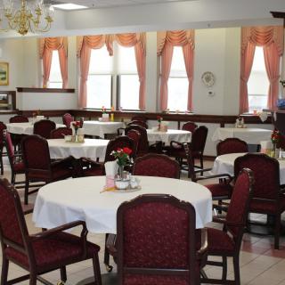 An elegant dining room with several tables covered in white tablecloths and adorned with flowers.