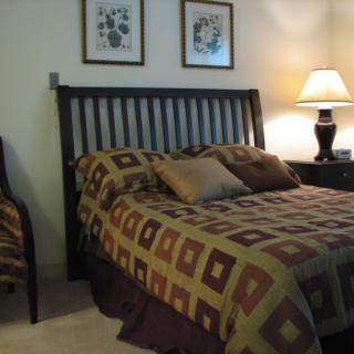A cozy bedroom with a patterned bedspread and two framed pictures on the wall.