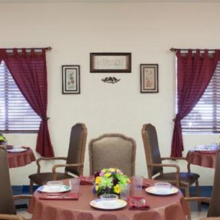 A neatly arranged dining room with tables, chairs, and decorative curtains.
