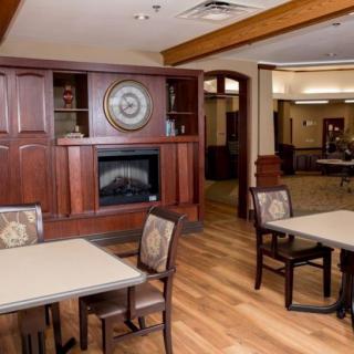 A cozy and well-furnished room featuring tables, chairs, a fireplace, and wooden decor.