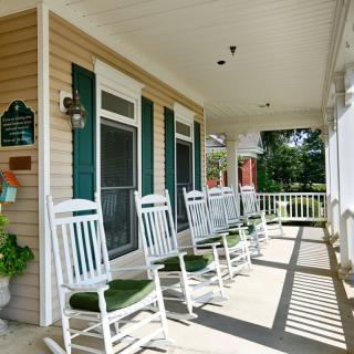 A cozy porch lined with white rocking chairs, perfect for relaxation.