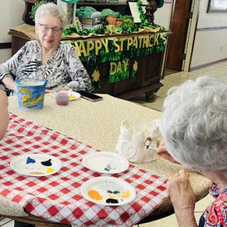 Elderly residents enjoying a crafting activity while celebrating St. Patrick's Day.