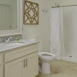 A clean and modern bathroom with a shower, sink, and toilet.