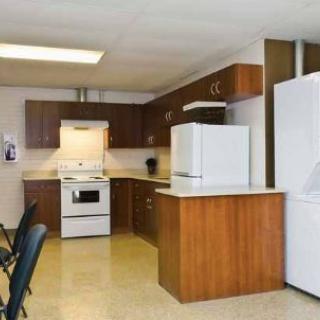 A kitchen interior featuring a stove, fridge, and wooden cabinets.