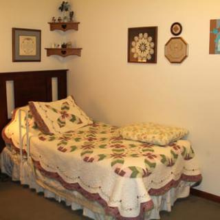 A cozy bedroom with a vintage quilt, wall art, and wooden shelves.