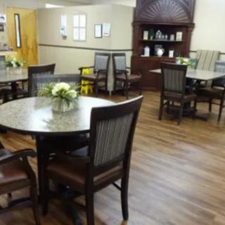 A cozy dining area with neatly arranged tables and chairs, featuring floral centerpieces.