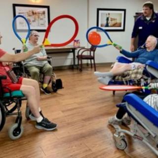 Elderly individuals enjoying a balloon game indoors, engaging in a fun community activity.