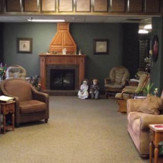A cozy living room featuring a fireplace, surrounded by armchairs and a sofa.