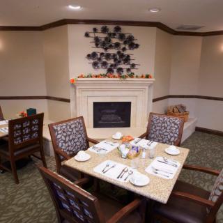 A cozy dining area with a neatly set table and a decorative fireplace.
