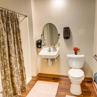 A clean and well-organized bathroom featuring a sink with a mirror, a toilet, and a shower curtain.