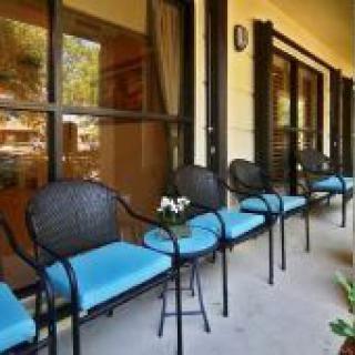 A row of chairs with blue cushions on a patio next to large windows.