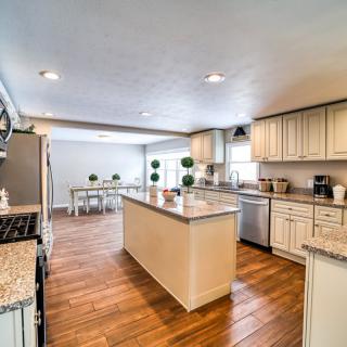 A modern kitchen with an island, wood flooring, and adjacent dining area.