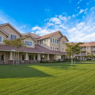 A spacious residential building with well-maintained lawns and clear blue skies.