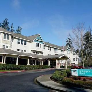 A residential building with a driveway and surrounding trees, featuring visible signage at the front.