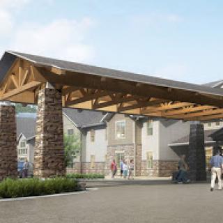 A beautifully designed entrance featuring a wooden canopy and stone pillars, leading into a residential area.