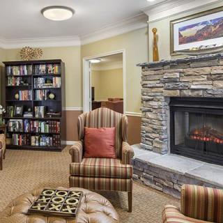 A cozy living room with a stone fireplace, comfortable armchairs, and a bookshelf filled with books.