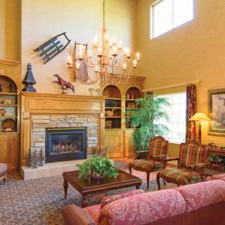 A spacious living room with a traditional design, featuring a fireplace, chandelier, and elegant furniture.