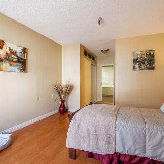A cozy bedroom with a neatly made bed, wooden flooring, and decorative wall art.