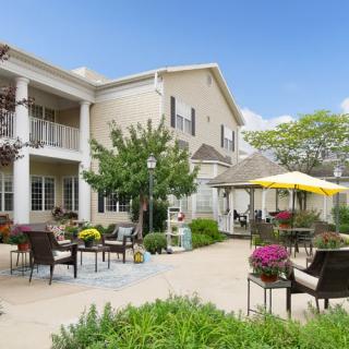 A beautifully landscaped patio area with outdoor furniture and vibrant flowers, adjacent to a residential building.