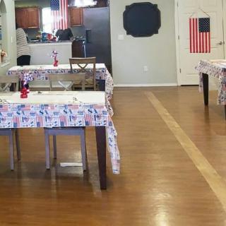 An indoor dining area with decorated tables and chairs, featuring tablecloths and flag-themed decor.