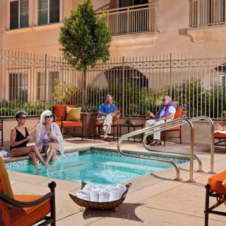 A group of people relaxing by a small outdoor pool on a sunny day.