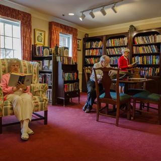 Elderly individuals enjoying a quiet reading session in a cozy library.