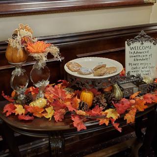 A cozy autumn display featuring colorful fall leaves, decorative pumpkins, and a plate of cookies, perfect for Thanksgiving.