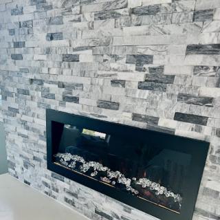 A sleek modern fireplace framed by a stylish stone wall, adding elegance to the living space.