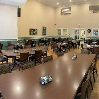 An empty dining hall with neatly arranged tables and chairs, ready for an event.