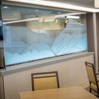 A beautifully designed glass window featuring a mountain motif, adding elegance to the restaurant's interior.